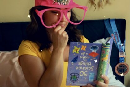 Woman sitting in a thinking pose with oversized goofy glasses reading an upside down book